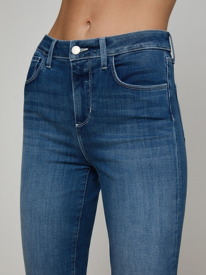 Close-up of a person wearing Kendra Cropped Flare Jean in dark denim wash with high waist, super stretch fabric, and button-zip closure, shown from waist to mid-thigh against a plain background.