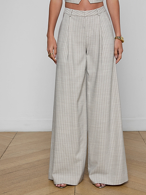 Someone stands on a wooden floor wearing the Allanah Pinstriped Trouser, a high-waisted, wide-leg modern pant in light gray Italian suit fabric with pressed pleats, paired with a matching cropped top.