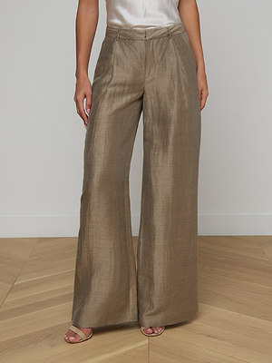 Wearing the Allanah Linen-Blend Trouser in light brown with a white sleeveless top, a person stands on a light wooden floor, only their lower half visible.