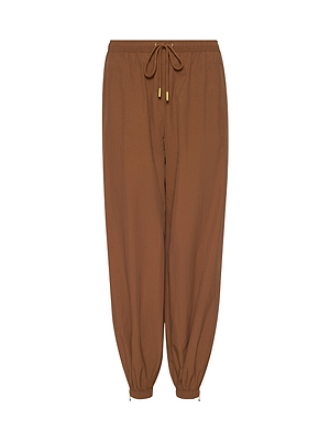 The Mariko Jogger, made from water-repellant nylon, features elastic cuffs, gold-tipped drawstrings, and a relaxed fit for a modern look—shown here in brown against a clean white background.