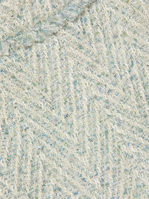 Close-up of Ashley Tweed Short’s textured, light-colored knit fabric featuring a subtle herringbone pattern, pale blue threads, and small shiny sequins for added sparkle.