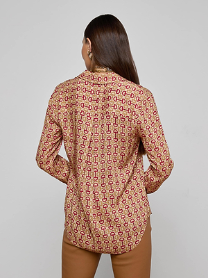 A woman with long brown hair, seen from behind, wears the L'AGENCE Holly Blouse—a slim fit, long sleeve button-down with a red geometric pattern—paired with brown pants against a plain light gray background.