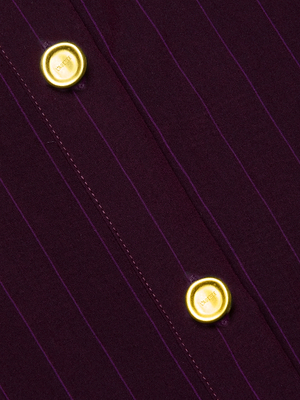 Close-up of the Cosette Pinstriped Shirt in dark purple organic cotton, featuring fine pinstripes and two gold decorative buttons embossed with a crest of a crown and lion.