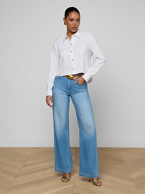 A woman in a white Cosette Shirt and blue jeans.