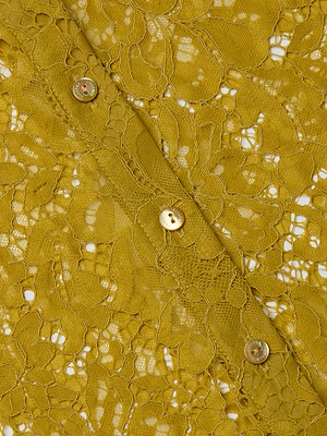 Close-up of the L'AGENCE Maia Floral Lace Blouse in mustard yellow, showcasing its delicate floral lace pattern and three small round buttons sewn along a diagonal seam.