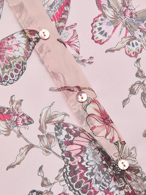 Close-up of the Laurent Blouse in sheer poly chiffon with a pink, white, and gray floral and butterfly jungle print. Features three small, round, shiny buttons sewn along a vertical seam.