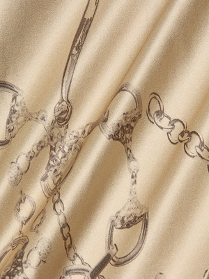 A close-up of smooth, beige satin with a horse bit chain print in sketch-like brown lines, perfect for the Calista Silk Camisole—showcasing gentle folds and elegant highlights ideal for a chic cropped top.