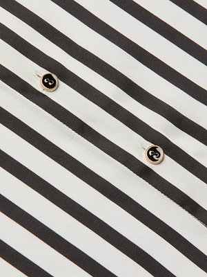 Close-up of the Eliora Shirt, a poly twill button-down featuring diagonal black and white stripes and two small round buttons with matching details.