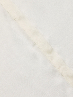Close-up of the Phoebe Silk Blouse in white or off-white charmeuse, showcasing a visible diagonal seam with subtle texture and detailed stitching.