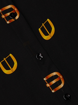 Close-up of the L'AGENCE Nina Silk Blouse, a relaxed fit black shirt with black buttons and a bold yellow-orange buckle print along the button placket.