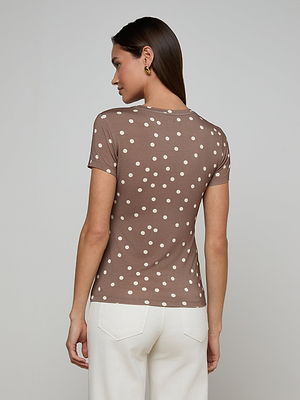 A woman with straight brown hair wears the bestselling Ressi Fitted Tee in brown with white polka dots and white pants, standing facing away from the camera against a plain light background.