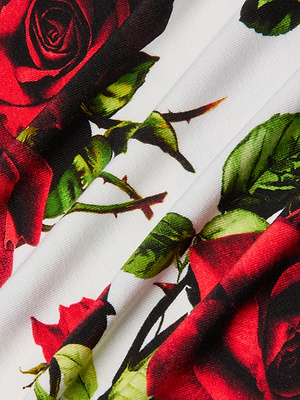Close-up of Ressi Fitted Tee in white stretch jersey knit, featuring vivid red rose and green leaf prints with detailed floral patterns and folded fabric texture.