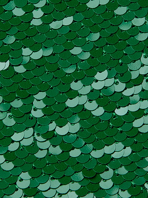 A close-up of emerald green sequins on the Karma Sequin Maxi Dress by L'AGENCE, arranged in a fish scale pattern that creates a textured, reflective surface.