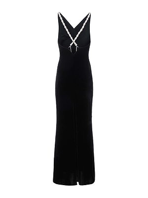 The Saint Velvet Gown by L'AGENCE is a sleeveless, floor-length black velvet dress with a fitted silhouette and white braided straps forming a V at the neckline.