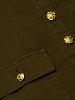 Close-up of L'AGENCE's Midy Button-Front Dress in olive green stretch cotton twill, featuring gold embossed buttons, visible stitching, and a pocket flap secured by one button.