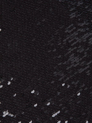 A close-up of small, glimmering black sequins overlapping on a surface—echoing the shimmering detail found on the L'AGENCE Lilith Sequin Dress.