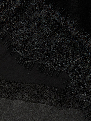Close-up of black lace with a floral pattern and scalloped edges layered over smooth black fabric, highlighting the elegance of the Elsa Silk Gown.