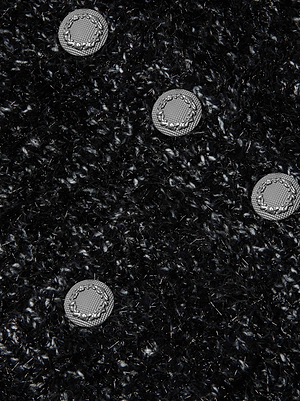 Close-up of the Una Knit Cardigan's textured black fabric, featuring four round silver-gray decorative buttons arranged diagonally across its surface.