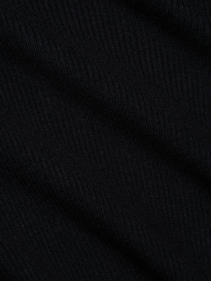 Close-up of the Colette Cropped Turtleneck’s ribbed knit fabric with diagonal lines, showcasing its textured surface and the subtle shadows formed by its folds.