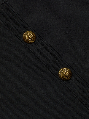 Close-up of the Patsy Cropped Cardigan in black power knit, featuring diagonal seams and two round signature buttons with a rope-like textured pattern.