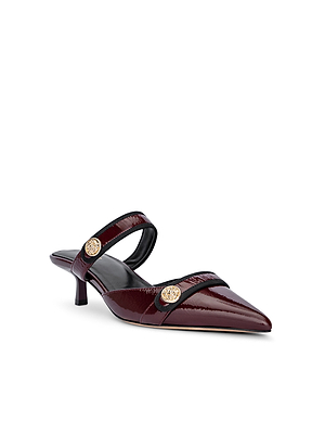 The Gilliane Heeled Mule by L'AGENCE features wine patent leather, a pointed toe, low kitten heel, and dual straps detailed with gold lion-embossed buttons for a chic vintage-contemporary look.