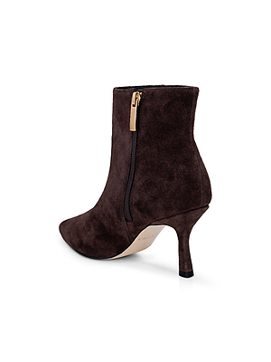 The Sylvie Suede Bootie by L'AGENCE is a dark brown pointed-toe bootie featuring a side zipper and slim stiletto heel, displayed on a white background.