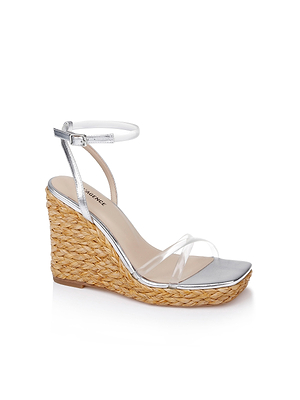 The Malone Wedge Espadrille features a braided raffia wedge heel, metallic silver sole, clear toe strap, and a white ankle strap with buckle, displayed on a white background.