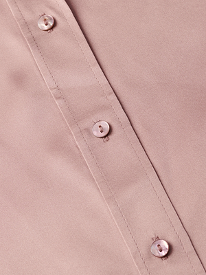 Close-up of the Dani Silk Blouse, a light pink silk button-down with a button placket featuring three shiny buttons and visible edge stitching.