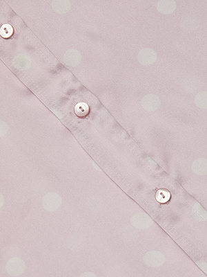 Close-up of the Ellah Silk Blouse in light pink, showcasing white polka dots and a row of small white buttons along the seam.