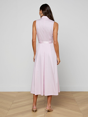 Woman wearing a light pink dress with a belt on a plain background