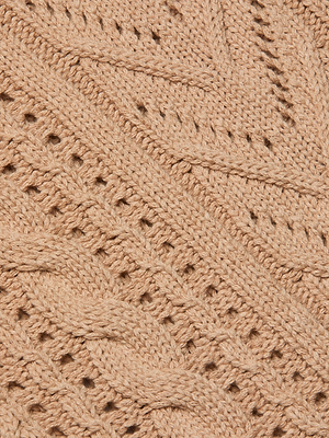 Close-up of the Mio Cabled Pullover, a beige cotton-blend knit with braided cable patterns, textured designs, small holes, and diagonal lines that highlight its detailed and soft woolen texture.