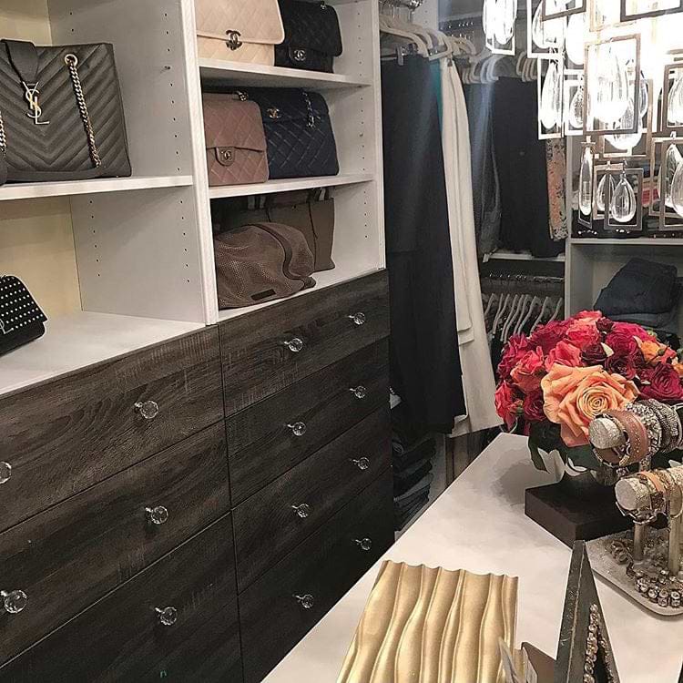 Grey closet with drawers and shelves displaying handbags