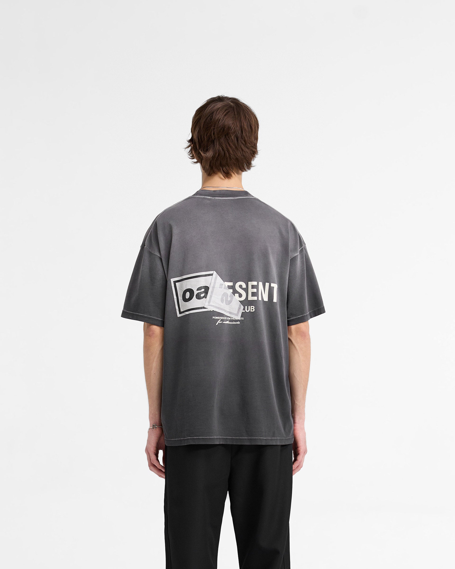 Man wearing a black t-shirt on a plain white background | Represent X Oasis Owners Club T-Shirt in Stained Black | Oversized fit t-shirt with dual logo and fly postered artwork | FW24 T-Shirts | Represent Clo