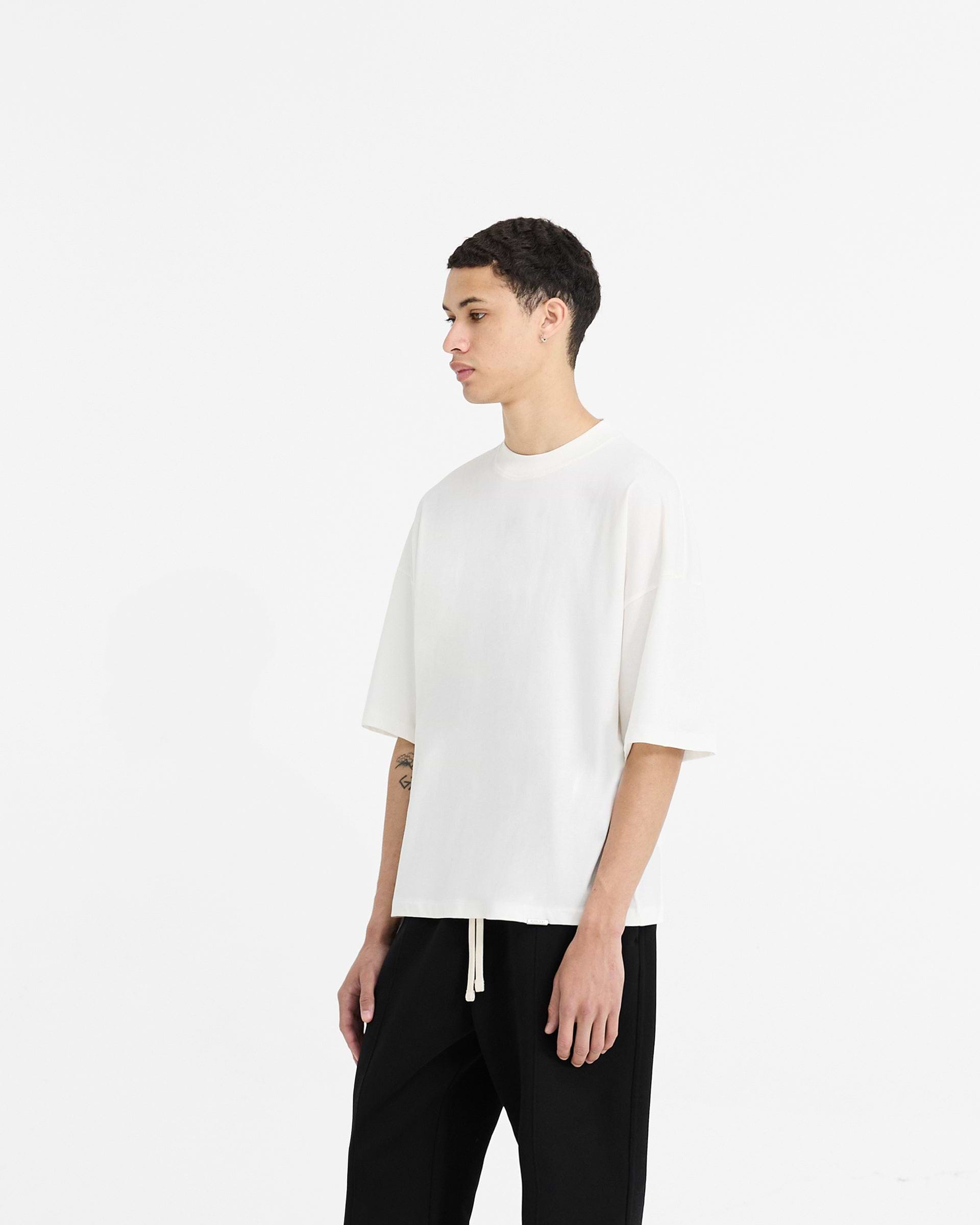 Back product image of a mens white t-shirt on a plain white background | Initial Boxy T-Shirt in Flat White | Oversized boxy cropped t-shirt with embroidered initial and metal bar logo | Initial T-Shirts | Represent Clo