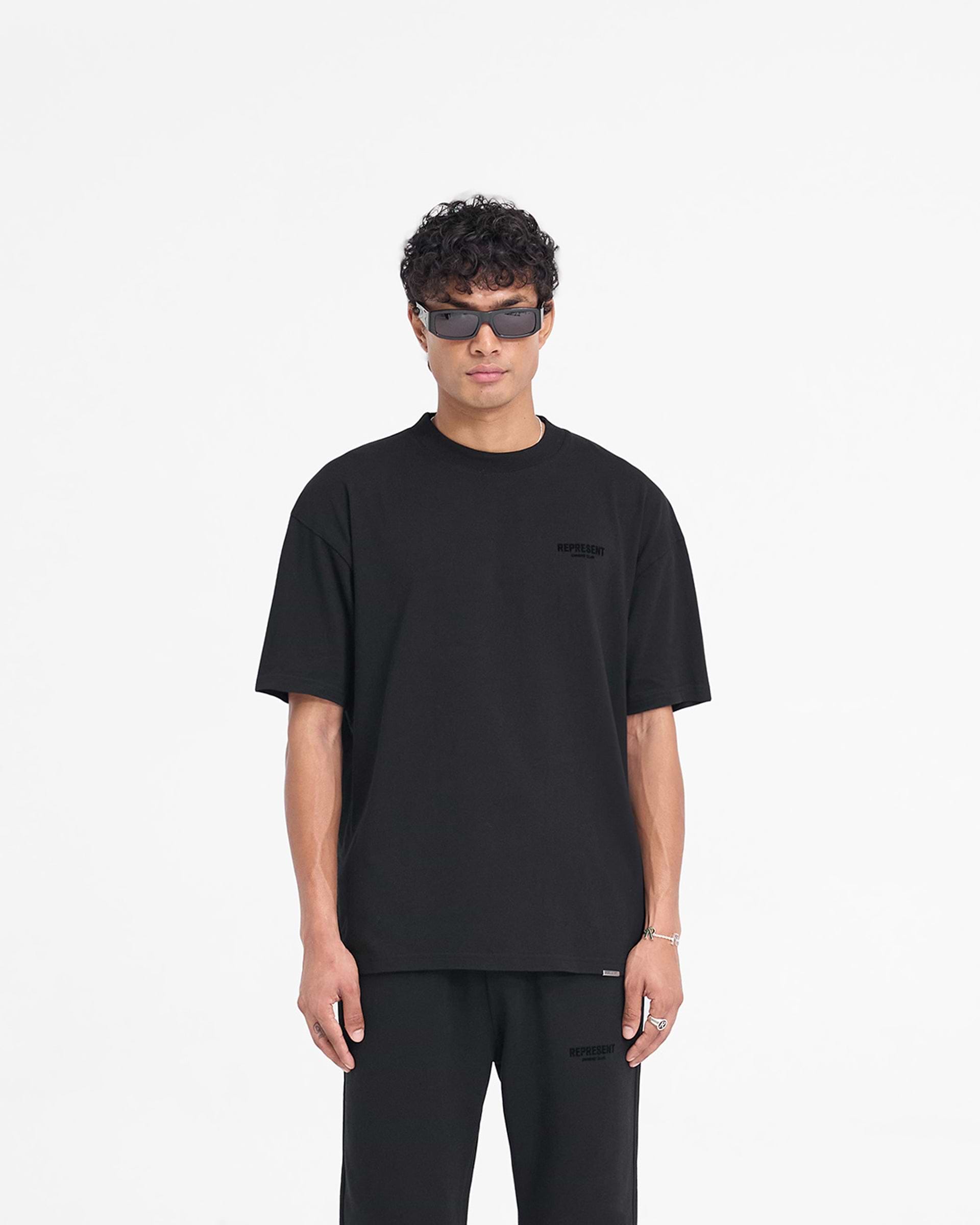 Man wearing a black t-shirt on a plain white background | Represent Owners Club Flocked T-Shirt in Black | Oversized t-shirt with flocking print | Owners Club T-Shirts | Represent Clo