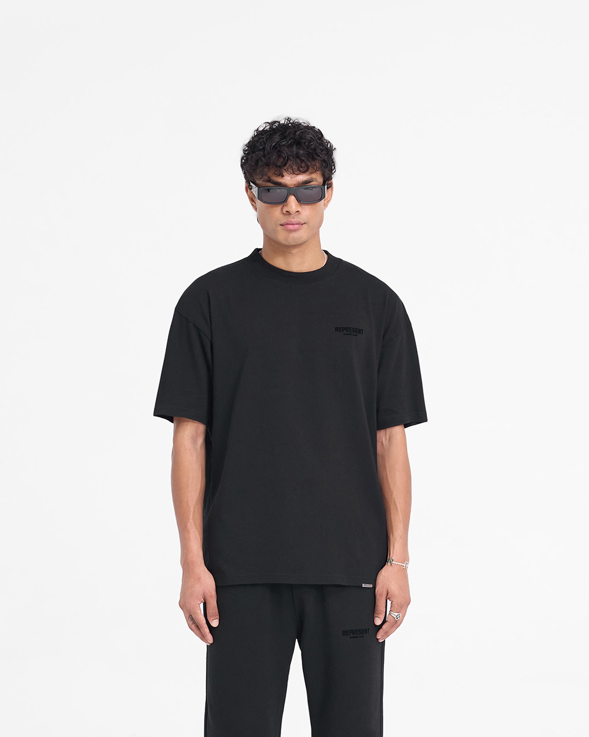 Man wearing a black t-shirt on a plain white background | Represent Owners Club Flocked T-Shirt in Black | Oversized t-shirt with flocking print | Owners Club T-Shirts | Represent Clo