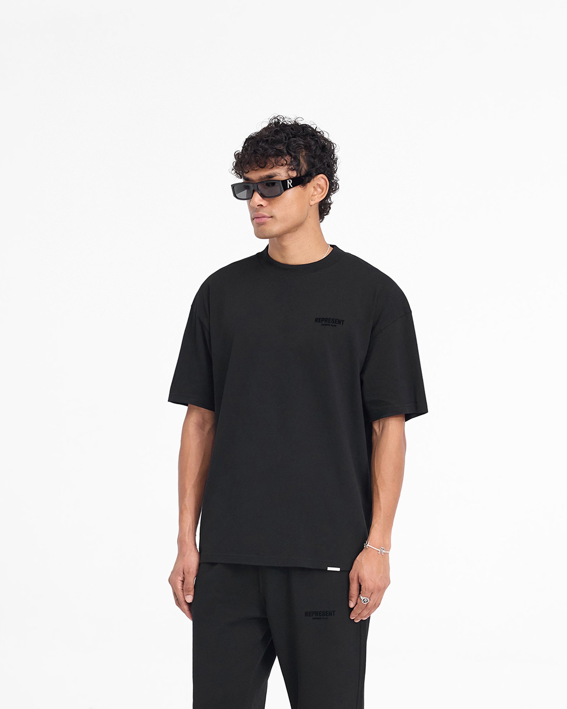 Man wearing a black t-shirt on a plain white background | Represent Owners Club Flocked T-Shirt in Black | Oversized short sleeve t-shirt with flocking print | Owners Club T-Shirts | Represent Clo