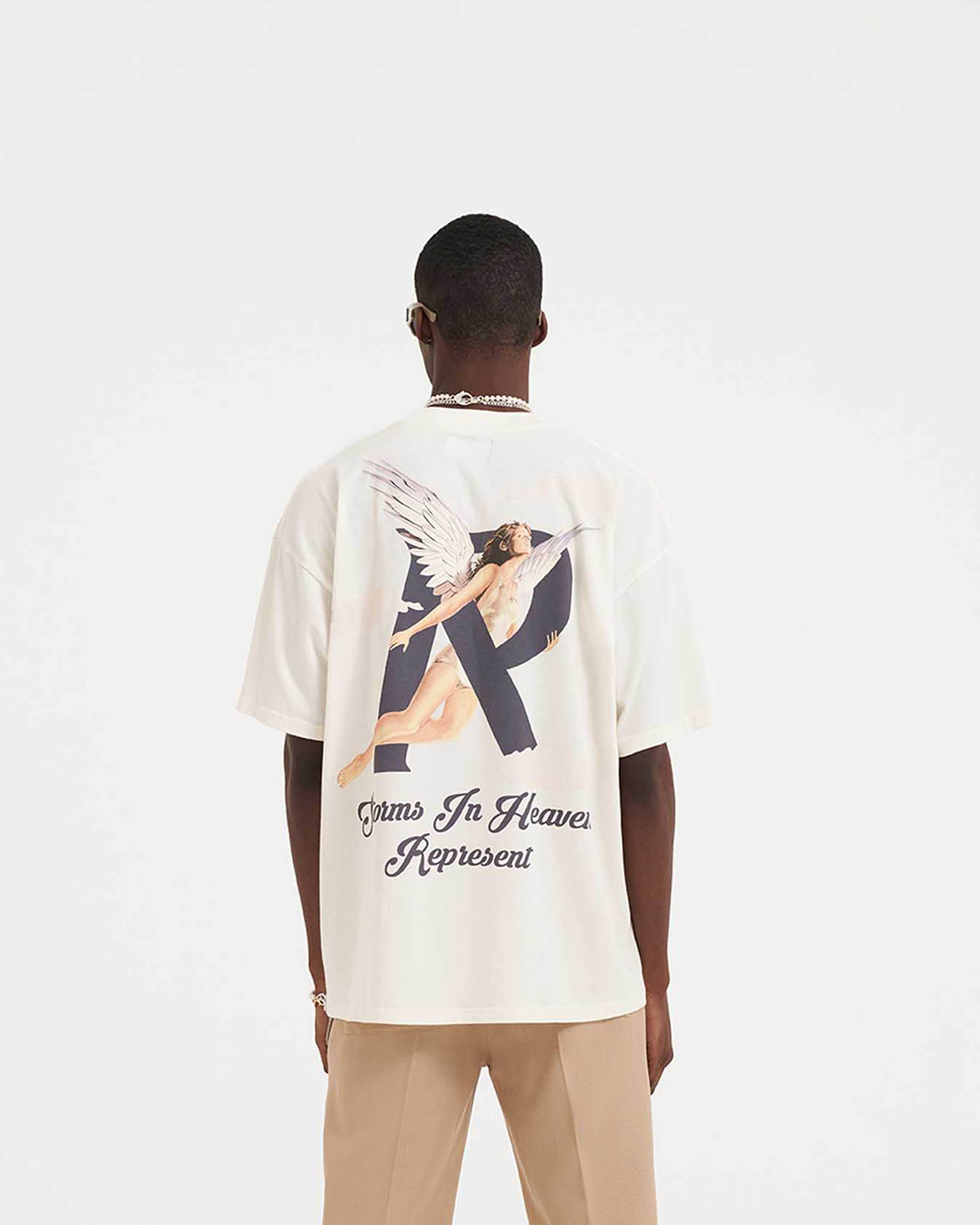 Man wearing a white graphic t-shirt on a plain white background | Storms In Heaven T-Shirt in Flat White | Oversized fit t-shirt with chest and back graphics | SS23 T-Shirts | Represent Clo