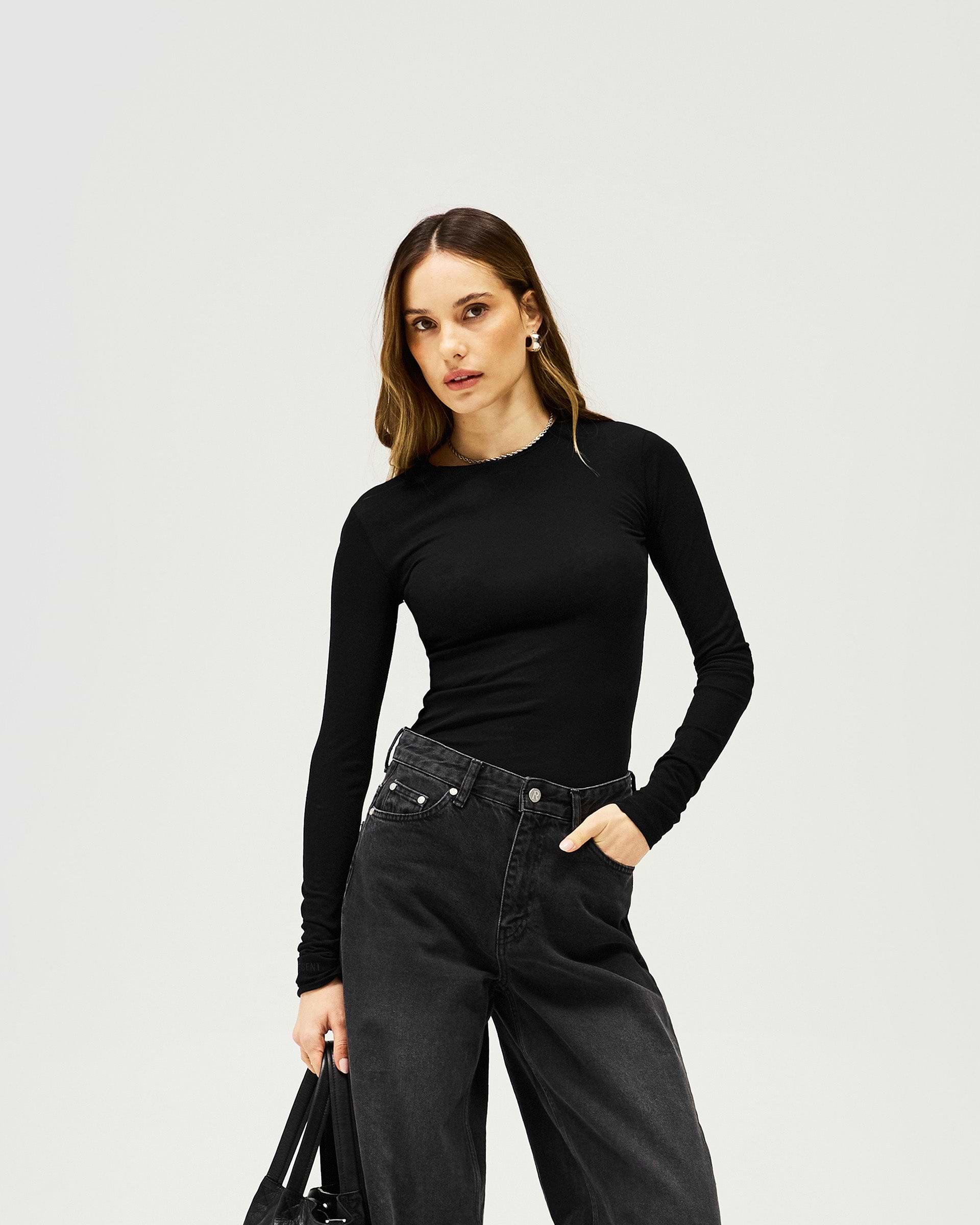 Woman wearing a black long sleeve top on a plain white background | Trigger Long Sleeve in Black | Slim fit slightly sheer shirt | Womens SS25 Knitwear | Represent Clo