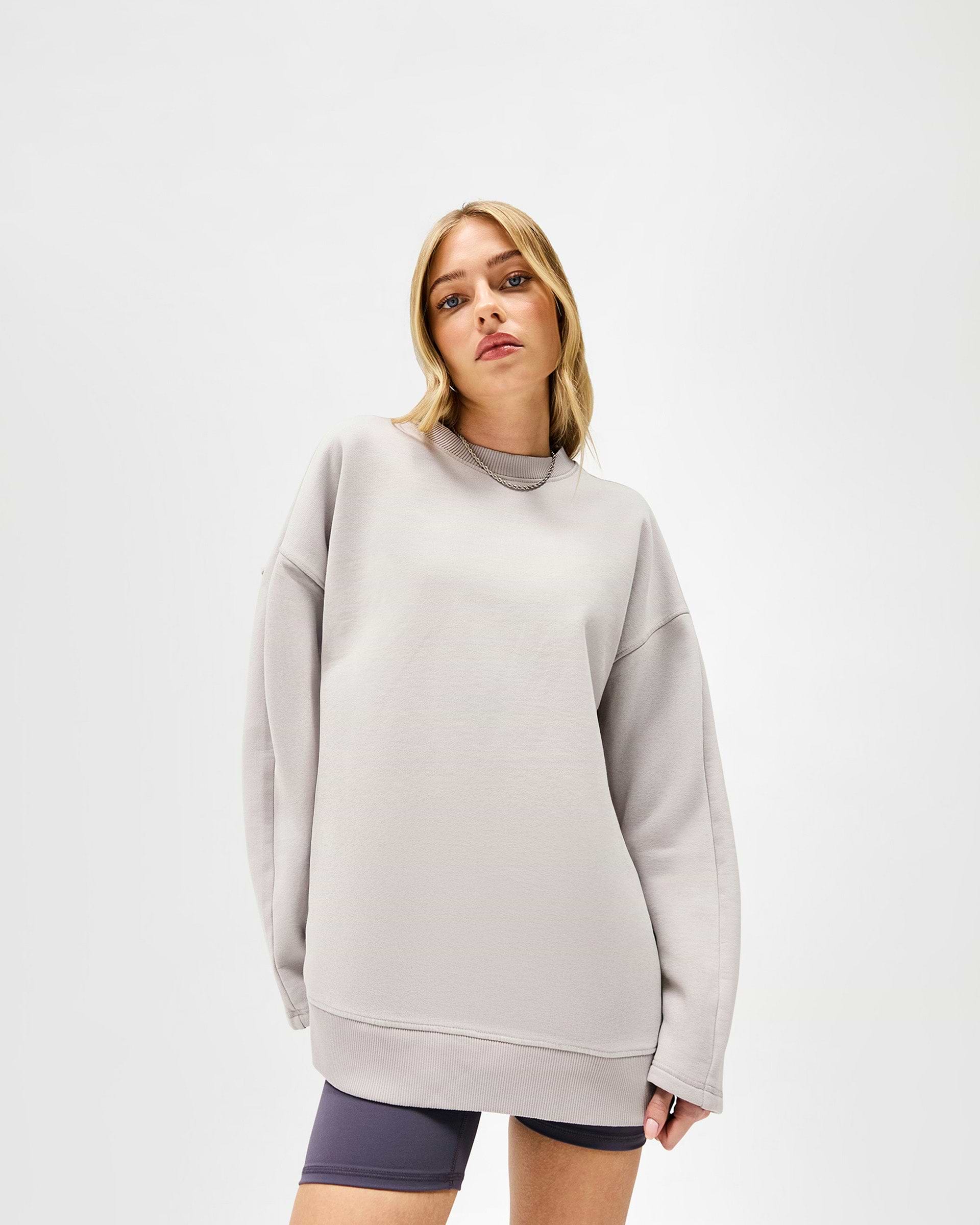 Woman wearing an oversized light grey sweater on a plain white background | Epic Raglan Sweater in Light Grey | Oversized fit raglan sweater with raw edge applique branding | Womens SS25 Sweaters | Represent Clo