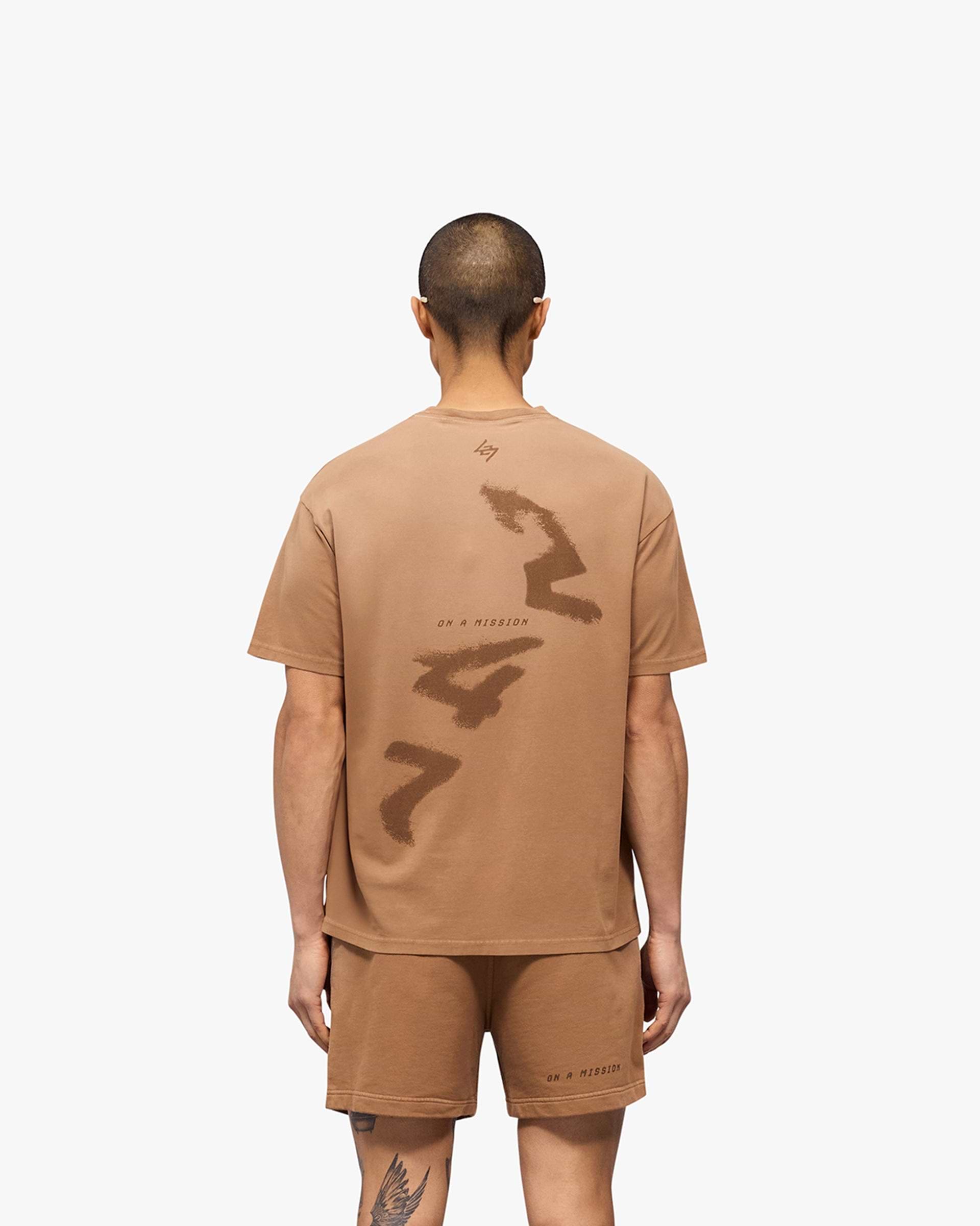 Man wearing an oversized rust t-shirt on a plain white background | 247 Motion Oversized T-Shirt in Rust | T-Shirt with water based graphic print | 247 T-Shirts | Represent Clo