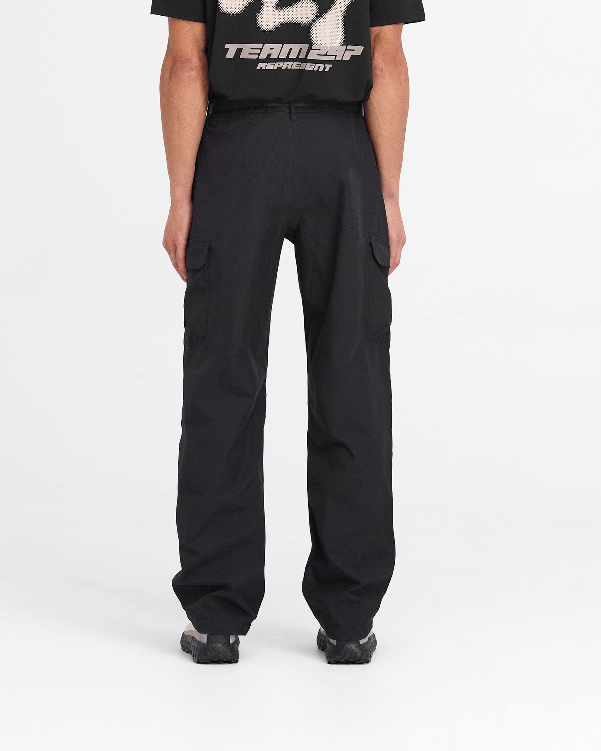 Man wearing black cargo pants on a plain white background | 247 Technical Cargo Pant in Black | Straight leg showerproof technical cargo pants | 247 Pants | Represent Clo