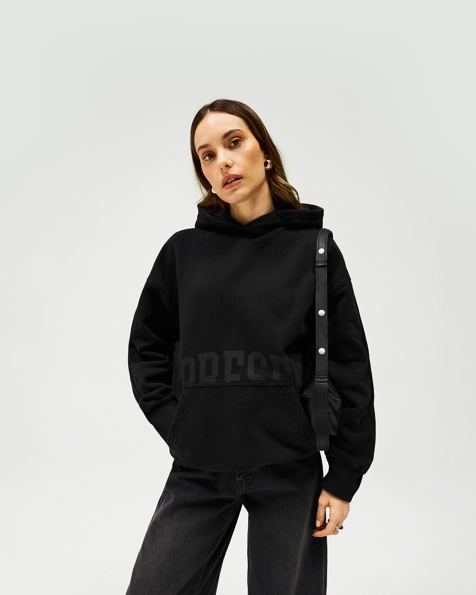 Woman wearing a brown hoodie on a plain white background | Boyfriend Graphic Hoodie in Black Coffee | Relaxed oversized hoodie with tonal branding | Womens SS25 Hoodies | Represent Clo