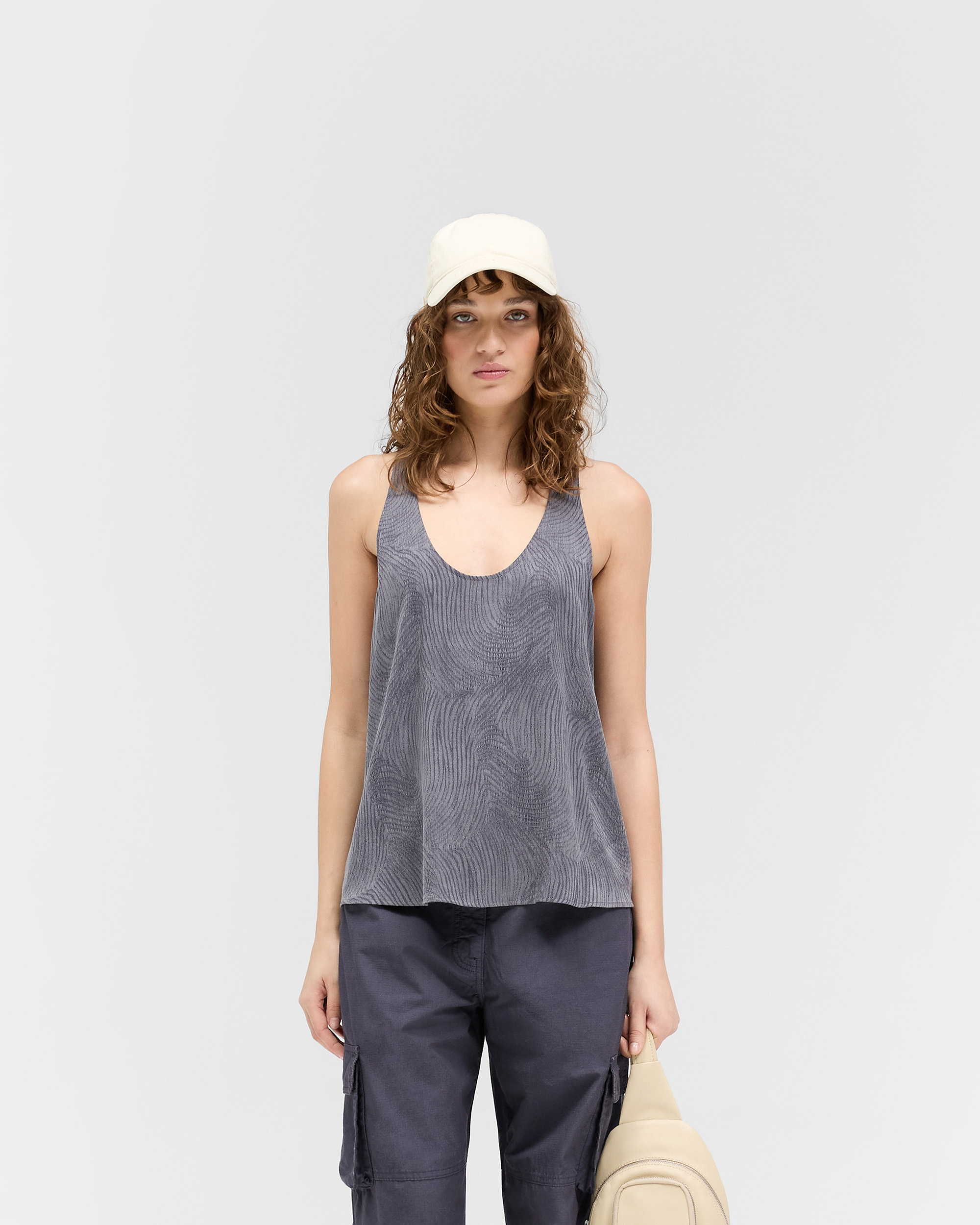Woman wearing a black vest top on a plain white background | Swirl Top in Jet Black | Low cut vest with extreme racer back detail | Womens SS25 Tops | Represent Clo