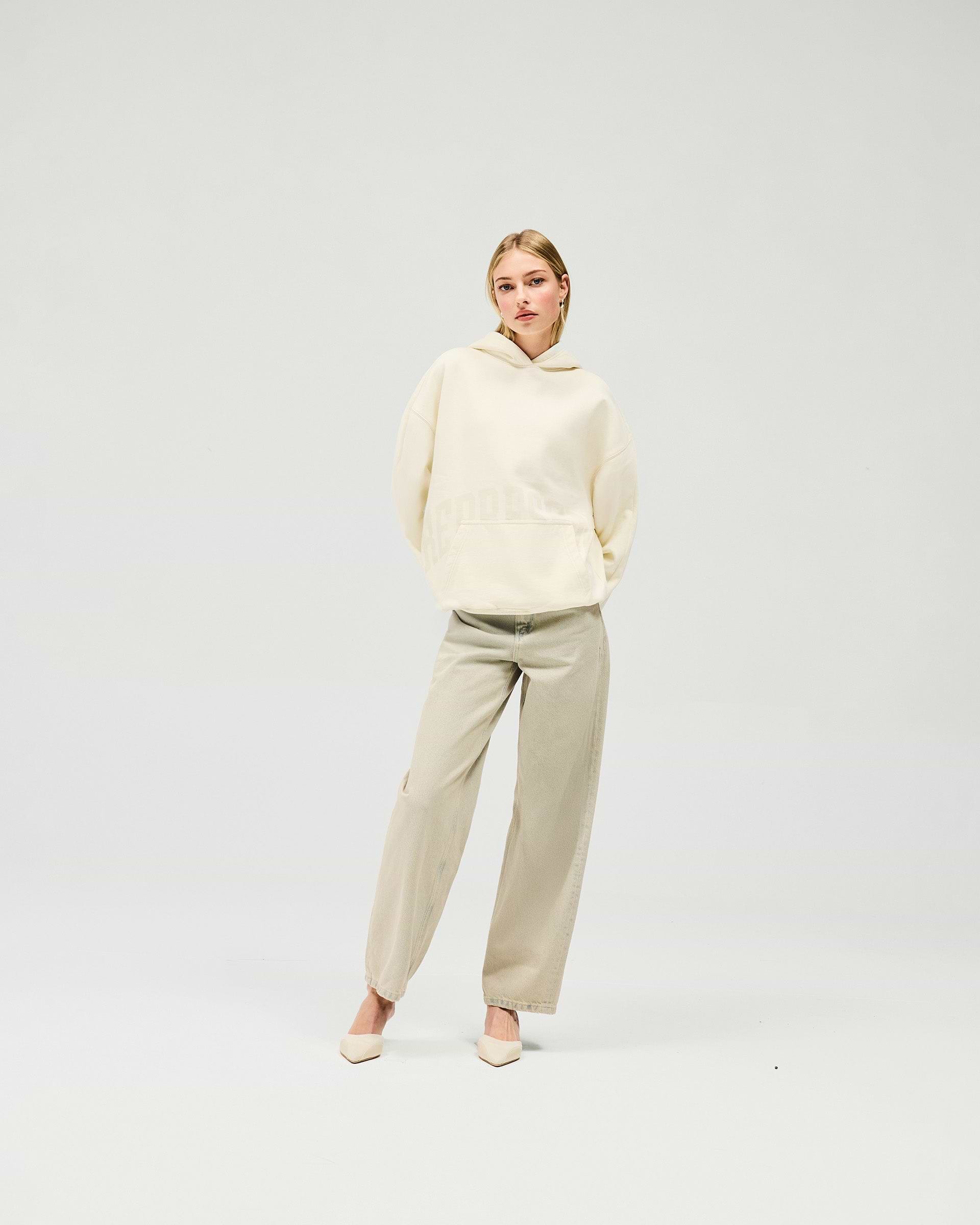 Woman wearing an oversized cream hoodie on a plain white background | Boyfriend Graphic Hoodie in Cream | Relaxed fit mid weight brushed fleece hoodie | Womens SS25 Hoodies | Represent Clo