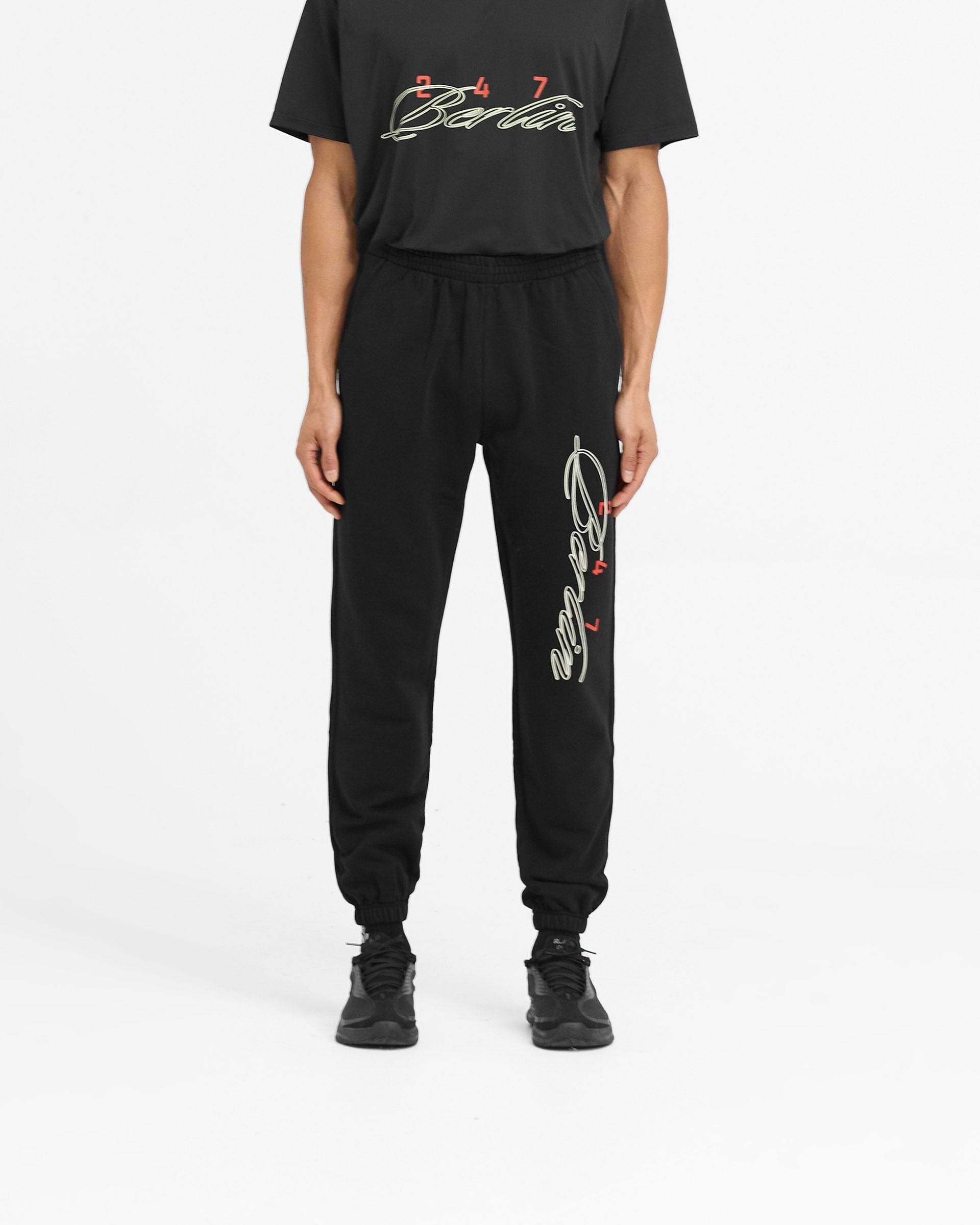 Man wearing black sweatpants with Berlin script on a plain white background | 247 Berlin Sweatpant in Black | Joggers with elasticated cuffs and internal drawcord | 247 Pants | Represent Clo