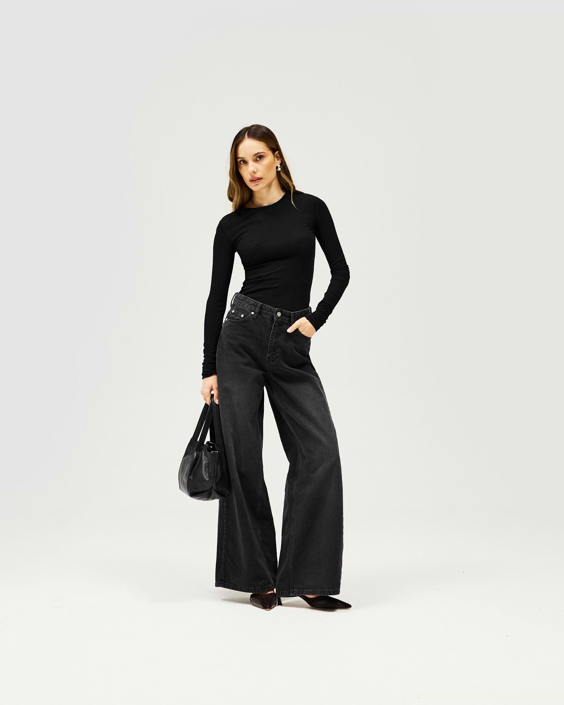 Woman wearing a black long sleeve knit top on a plain white background | Trigger Long Sleeve in Black | Slim fit slightly sheer knitted top | Womens SS25 Knitwear | Represent Clo