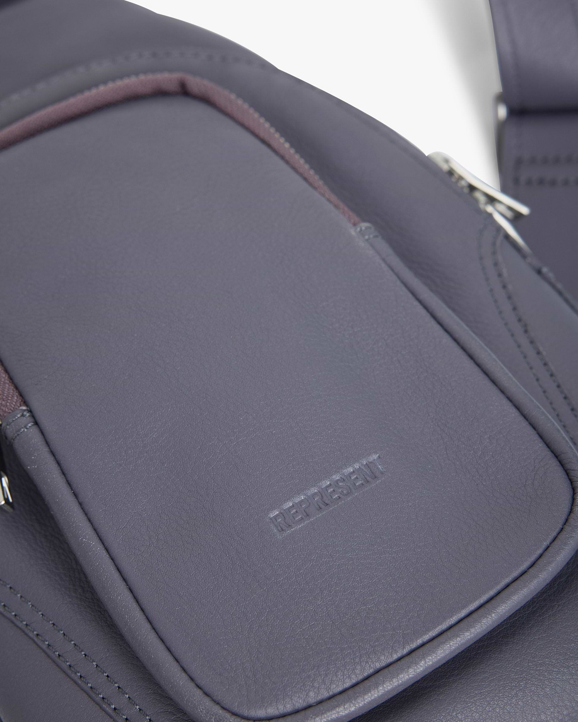 Back product image of a womens grey sling bag on a plain white background | Utility Sling Bag in Excalibur | Soft full grain leather sling bag with adjustable strap | SS25 Accessories | Represent Clo
