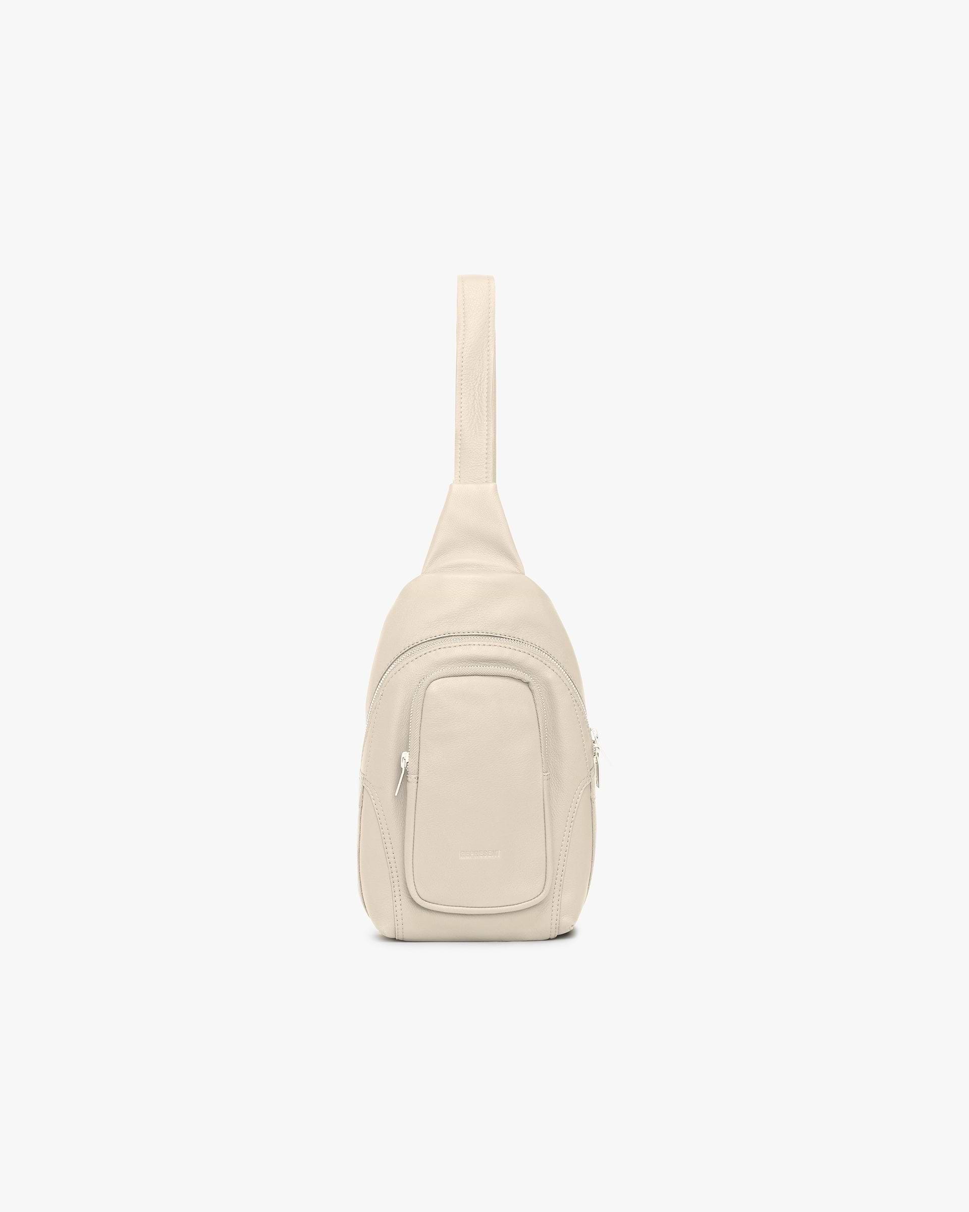 Front product image of a womens cream bag on a plain white background | Utility Sling Bag in Cream | Functional sling bag with adjustable strap | Womens SS25 Accessories | Represent Clo