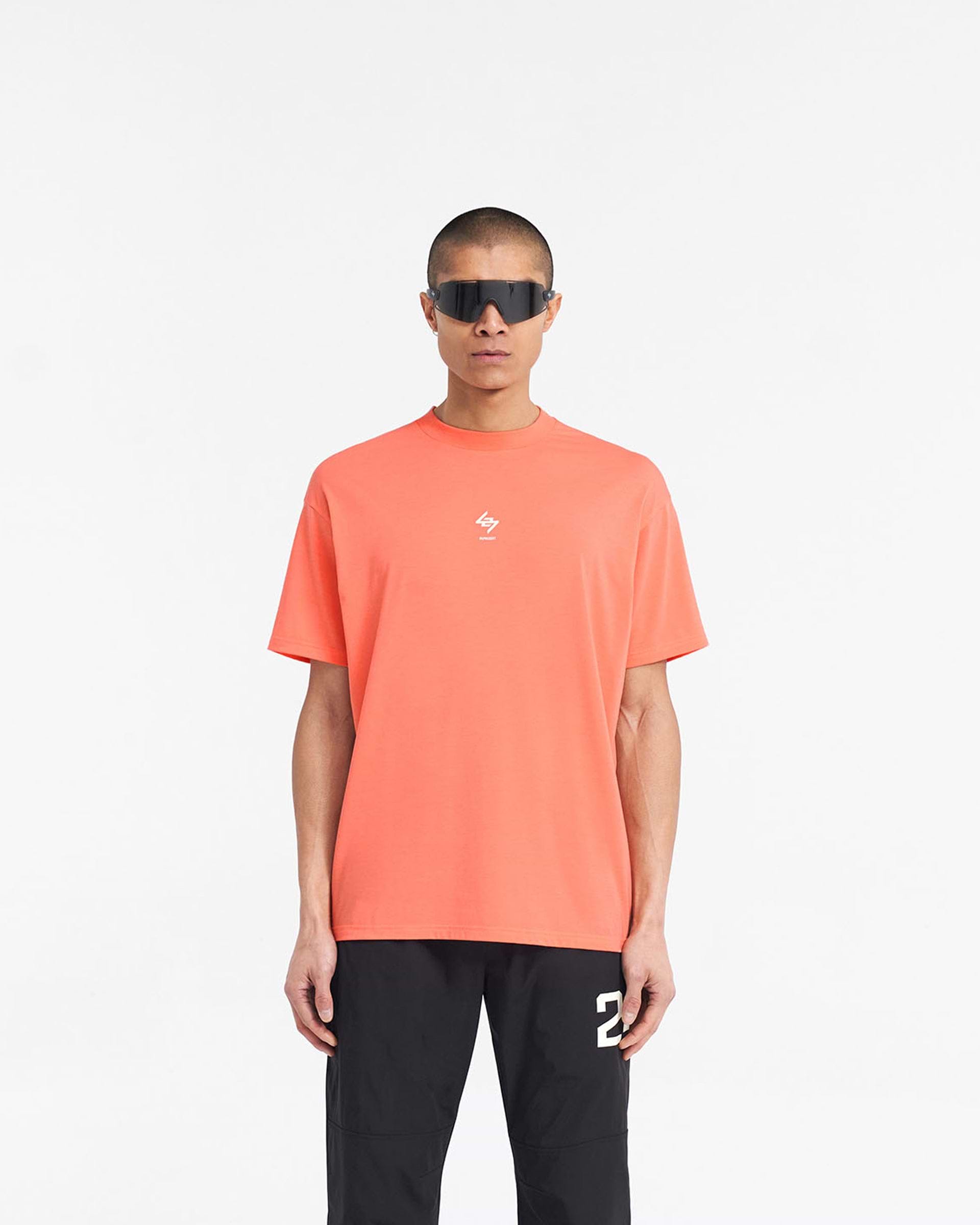 Man wearing an oversized coral t-shirt on a plain white background | 247 Oversized T-Shirt in Coral | Lightweight gym t-shirt with 4-way stretch | 247 T-Shirts | Represent Clo